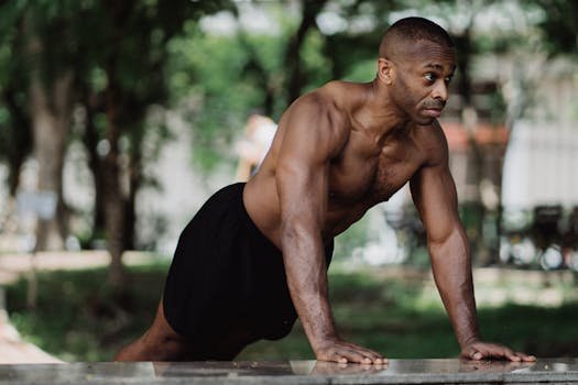 Muscular man performing a push-up outdoors, showcasing strength and fitness in a natural setting.