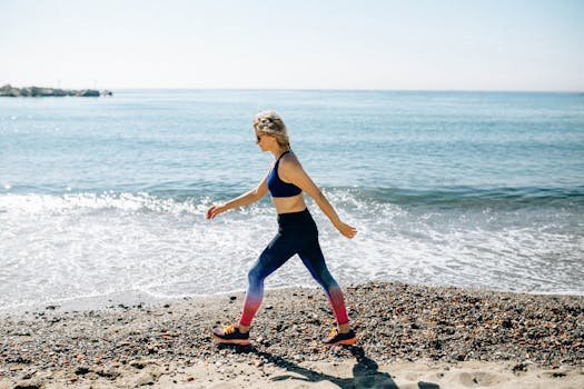 A woman in activewear power walks along a sunny beach shore, enjoying the healthy lifestyle and ocean view.