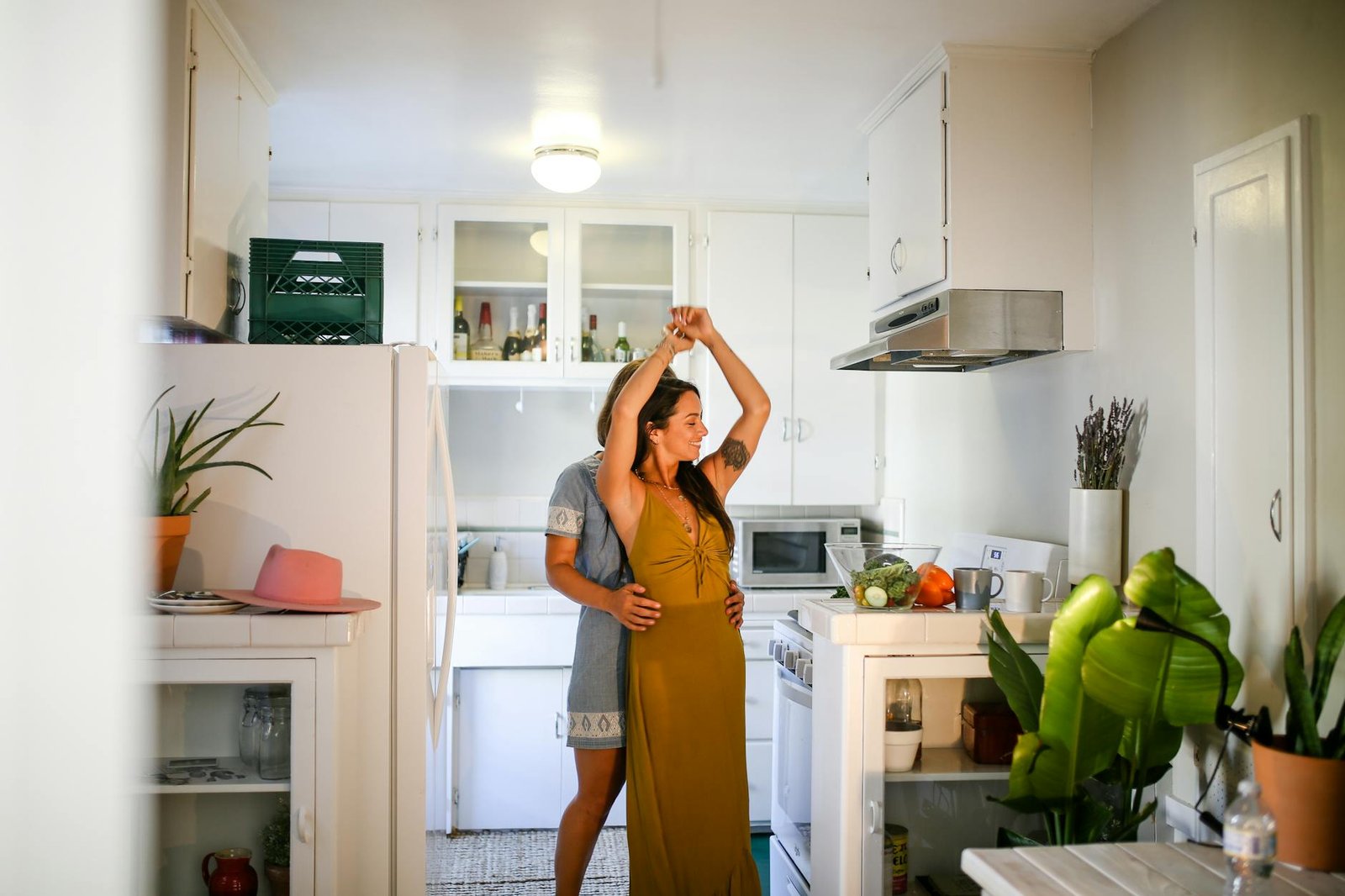 A couple shares a romantic moment dancing together in their cozy kitchen setting.